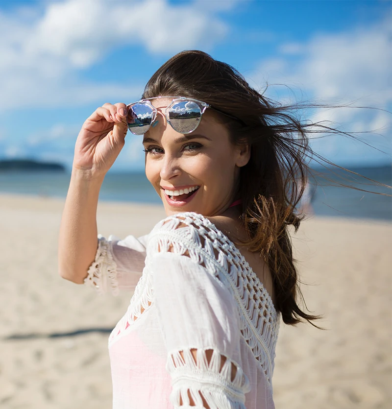 Happy woman on beach lifting shades up